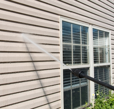 Pressure washing stream cleaning siding on a house